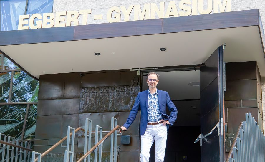 Mann steht vor dem Eingang, über dem "Egbert-Gymnasium" in goldenen Lettern steht