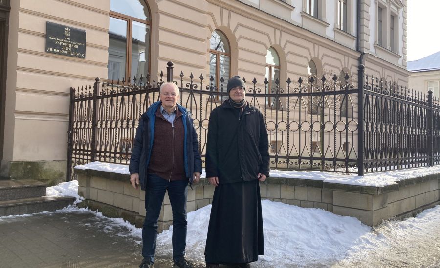 Zwei Männer vor einem Zaun an einem Gebäude