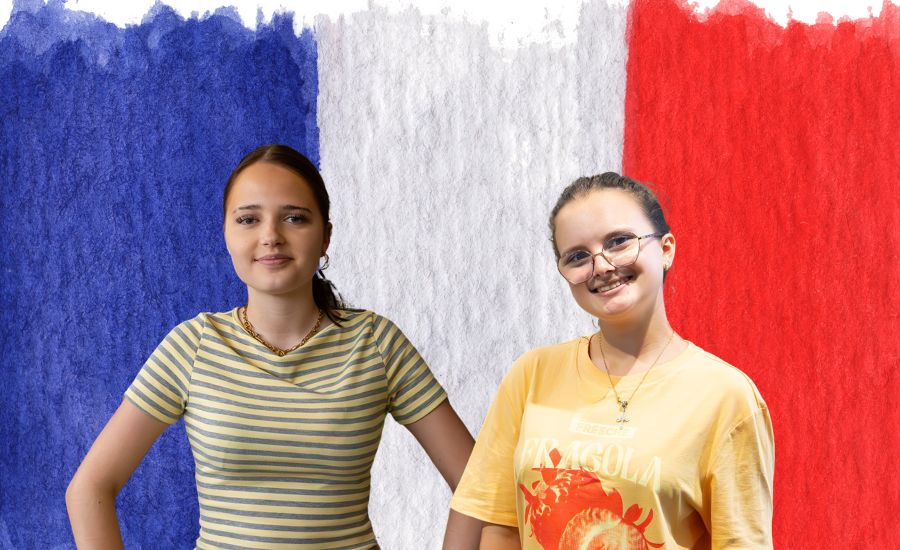 Zwei Schülerinnen vor der französischen Flagge