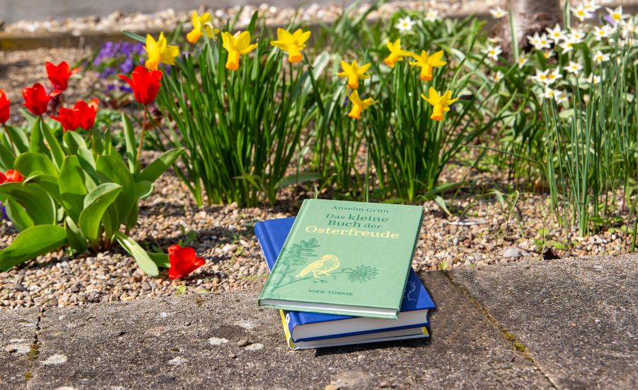 Bücherstapel vor einem Blumenbeet