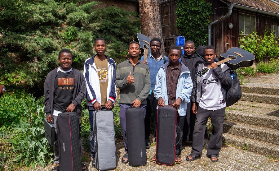 Sieben junge Männer aus Tansania im Grünen mit ihren Instrumenten