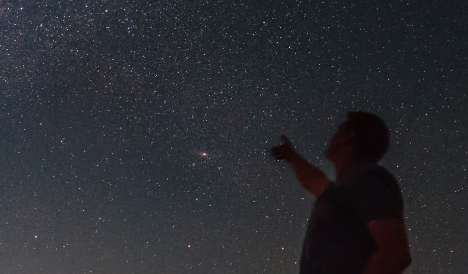 Mann zeigt auf den Sternenhimmel