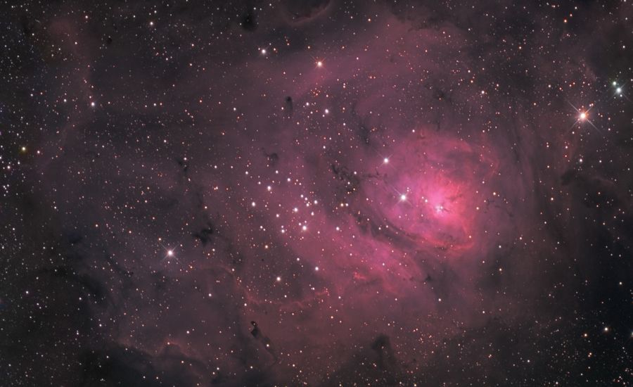 Blick ins Weltall auf Sterne umhüllt von einem roten Nebel