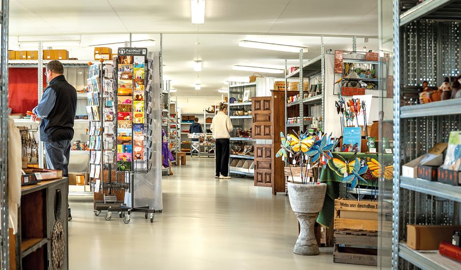 Blick in den Fair-Handel, Menschen stehen vor Regalen voller bunter Produkte