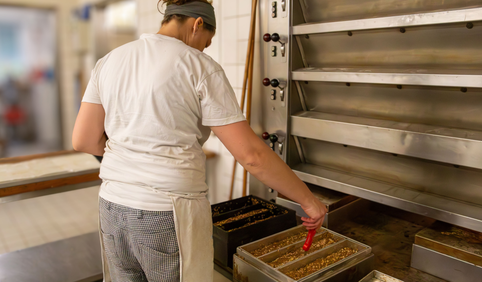 Frau steht am Ofen und misst Temperatur in Brotform